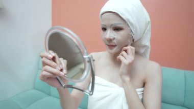 Spa konsepti 4k Çözünürlük. Evde maske takan Asyalı bir kadın. Yüz bakımı. Nemi geri getirmek için serum.