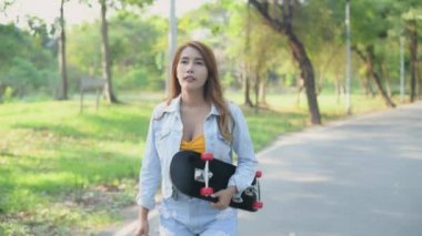 Bağımsız 4k Çözünürlük kavramı. Parkta kaykay tutan Asyalı kadın..