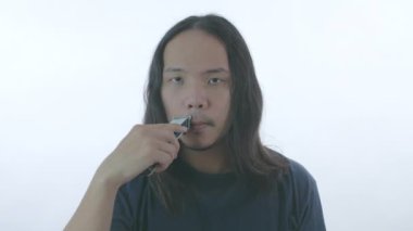 Sağlık konsepti 4k Çözünürlük. Genç Asyalı bir adam makasıyla tıraş oluyor..