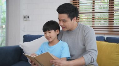 Aile kavramı 4k Kararlılığı. Baba çocuklara evde kitap okumayı öğretiyor. Ebeveynler, oğullarına ödev yaptırıyor..