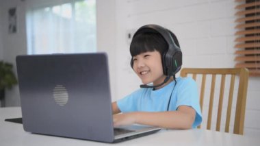 Teknoloji konsepti 4k Çözünürlük. Asyalı çocuk evde bilgisayar oyunu oynuyor. Zafer sevinci.