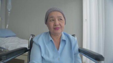 Sağlık konsepti 4k Çözünürlük. Hasta mutlu bir şekilde gülümsüyordu. Pencereden dışarı bak. Tekerlekli sandalyede oturan Asyalı kadın.