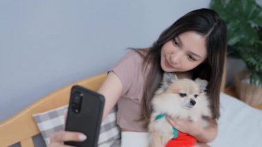 Tatil konsepti 4k Çözünürlük. Asyalı kızlar yatak odasında cep telefonlarıyla oynuyorlar. Akıllı bir telefonla fotoğraf çek..