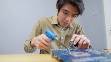 Teknoloji konsepti 4k Çözünürlük. Evdeki elektronik devreleri bağlayan Asyalı bir adam. bilgisayar onarımı.