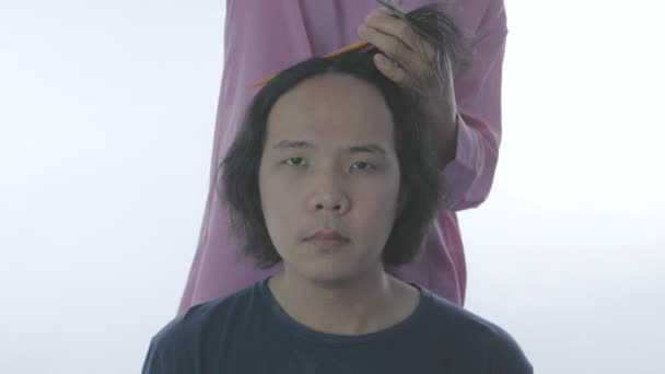 4K解像度のヘアケアコンセプト 白い背景にアジア系の男性が髪を切っている お客様のための美容師の切断髪 — ストック動画