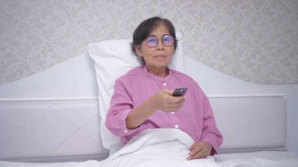 假日4K解像度的概念 亚洲老太太在卧室看电视 — 图库视频影像