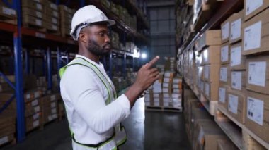 4k Kararlılığın iş konsepti. Afrikalı adam depoda malları kontrol ediyor. Yurtdışından ithal ürünlerin veri koleksiyonu.