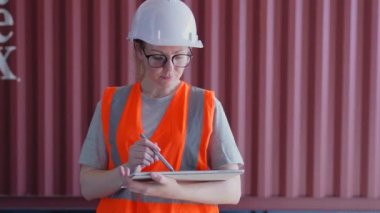 4k Kararlılığın iş konsepti. Bir çalışan depodaki tabletle malları kontrol ediyor. Verileri kaydet ve dışarıya aktar.