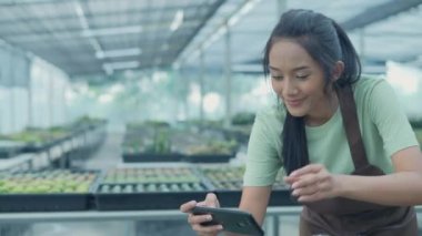 4k Kararlılığın iş konsepti. Bahçede kaktüs fotoğrafı çeken Asyalı kadın. İnternette cep telefonuyla ürün satmak.