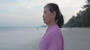 Seyahat konsepti 4k Çözünürlük. Asyalı yaşlı bir kadın kumsalda mutlu bir şekilde nefes alıyor..