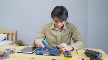 Teknoloji konsepti 4k Çözünürlük. Evdeki elektronik devreleri bağlayan Asyalı bir adam. bilgisayar onarımı.