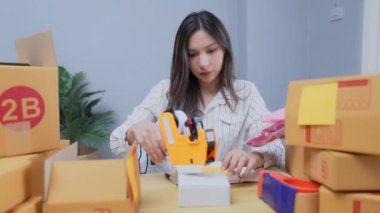 4k Kararlılığın iş konsepti. Asyalı kadın evdeki kutularda ürünleri paketliyor..