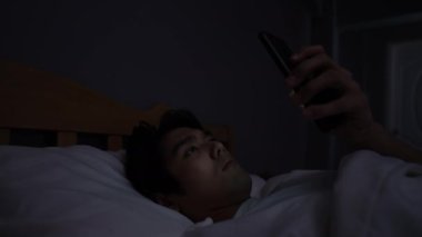 Tatil konsepti 4k Çözünürlük. Genç Asyalı adam yatak odasında cep telefonu çalıyor..
