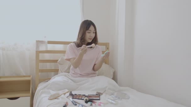 4K解像度の美しさの概念 アジアの女の子はベッドルームでベッドで化粧をする — ストック動画