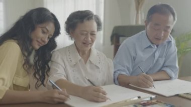 Sanatçı konsepti 4k Çözünürlük. Asyalı aileler oturma odasında bir araya geliyorlar. Sanatçı iş yaratıyor. Boş zaman aktiviteleri ve hobileri.