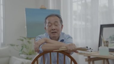 Sanatçı konsepti 4k Çözünürlük. Asyalı erkek sanatçı oturma odası sanatını nasıl yaratacağını anlatıyor. Boş zaman aktiviteleri ve hobileri.