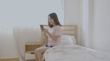 Tatil konsepti 4k Çözünürlük. Asyalı kızlar yatak odasında cep telefonu oynuyorlar..