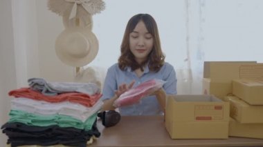 4k Kararlılığın iş konsepti. Asyalı kadın evdeki kutularda ürünleri paketliyor..