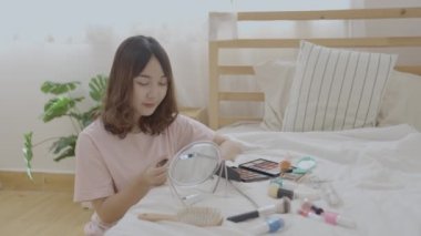 4k Çözünürlük 'ün güzellik konsepti. Asyalı kızlar yatak odasındaki yatakta makyaj yaparlar..