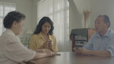 Tatil konsepti 4k Çözünürlük. Asyalı aileler evde oyun oynarken sırayla kart atıyorlar. Aile kumar oyunları.