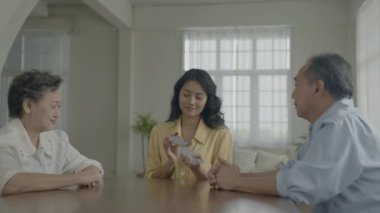 Tatil konsepti 4k Çözünürlük. Asyalı aileler evde oyun oynarken sırayla kart atıyorlar. Aile kumar oyunları.