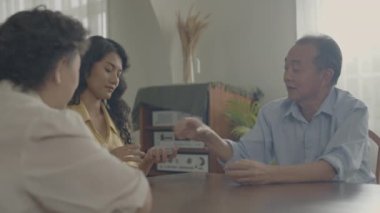 Tatil konsepti 4k Çözünürlük. Asyalı aileler evde oyun oynarken sırayla kart atıyorlar. Aile kumar oyunları.
