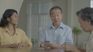 Tatil konsepti 4k Çözünürlük. Asyalı aileler evde oyun oynarken sırayla kart atıyorlar. Aile kumar oyunları.