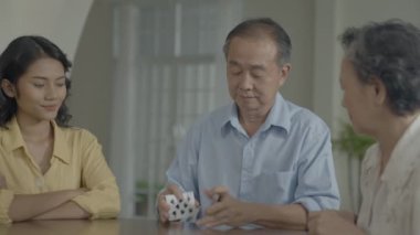 Tatil konsepti 4k Çözünürlük. Asyalı aileler evde oyun oynarken sırayla kart atıyorlar. Aile kumar oyunları.