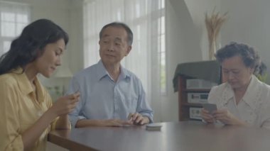 Tatil konsepti 4k Çözünürlük. Asyalı aileler evde oyun oynarken sırayla kart atıyorlar. Aile kumar oyunları.