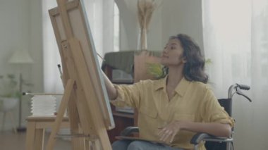 Sanatçı konsepti 4k Çözünürlük. Asyalı kadın oturma odasında resim çiziyor. Sanatçı iş yaratıyor. Engelli insanlar hobi yaratıyor..