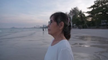 Seyahat konsepti 4k Çözünürlük. Sahilde kendinden emin gülümseyen Asyalı yaşlı kadın..