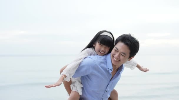 假日4K解像度的概念 父亲和女儿在海滩上玩耍 亚洲女孩挥动她的手要飞 — 图库视频影像