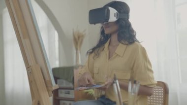 Sanatçı konsepti 4k Çözünürlük. VR giyip oturma odasında resim yapan Asyalı bir kadın. Sanatçı iş yaratıyor. Boş zaman aktiviteleri ve hobileri.