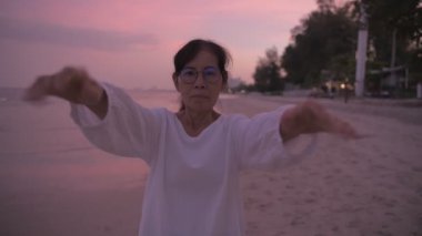Seyahat konsepti 4k Çözünürlük. Asyalı yaşlı bir kadın kumsalda mutlu bir şekilde nefes alıyor..
