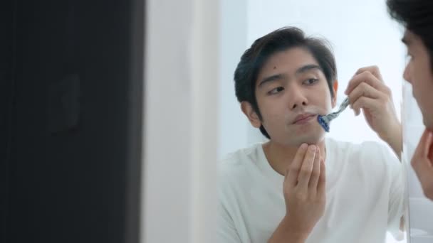 4K解像度の健康コンセプト 若いアジア人男性はバスルームでシェービング 鏡を見て — ストック動画