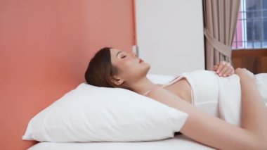 Tatil konsepti 4k Çözünürlük. Asyalı kızlar sabahları yataktan çıkmak istemezler. Cep telefonu alarmı. Uyanırken tembellik.