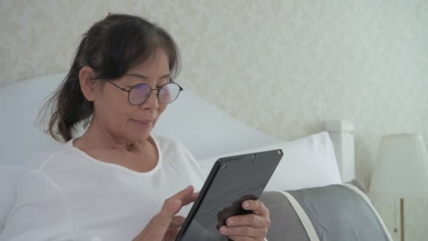 Koncepcja Wakacyjna Rozdzielczości Azjatycka Staruszka Korzystająca Tabletu Sypialni — Wideo stockowe