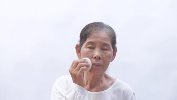 4K分辨率的美感概念 亚洲老年妇女高兴地将粉末涂在苍白的背景上 — 图库视频影像