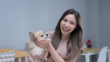 Tatil konsepti 4k Çözünürlük. Asyalı bir kadın evinde röportaj veriyor. Evde köpek büyütmekten bahsediyorum..