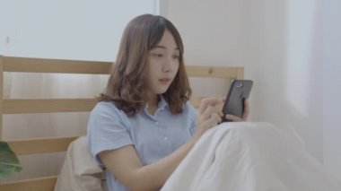 Tatil konsepti 4k Çözünürlük. Asyalı kızlar yatak odasında cep telefonu oynuyorlar..