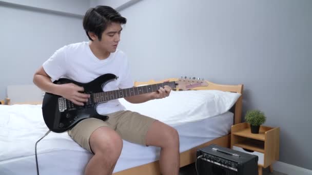 Concept Vacances Résolution Asiatique Homme Pratiquant Guitare Électrique Dans Chambre — Video