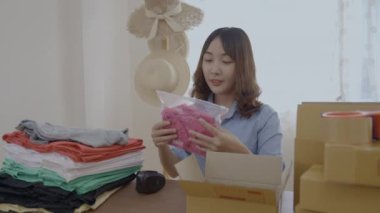 4k Kararlılığın iş konsepti. Asyalı kadın evdeki kutularda ürünleri paketliyor..