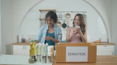 4k Çözünürlük Gönüllü konsepti. Asyalı kadınlar evde bağış kutusunda yiyecek paketliyorlar. Kurbanlara yardım etmek için bağışlanan tüketici malları.