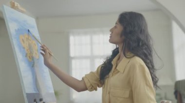 Sanatçı konsepti 4k Çözünürlük. Asyalı kadın oturma odasında resim çiziyor. Sanatçı iş yaratıyor. Boş zaman aktiviteleri ve hobileri.