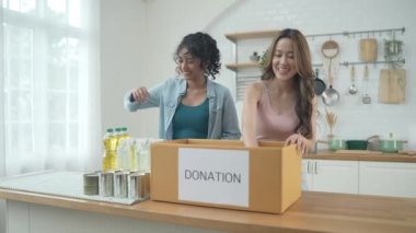 4k Çözünürlük Gönüllü konsepti. Asyalı kadınlar evde bağış kutusunda yiyecek paketliyorlar. Kurbanlara yardım etmek için bağışlanan tüketici malları.