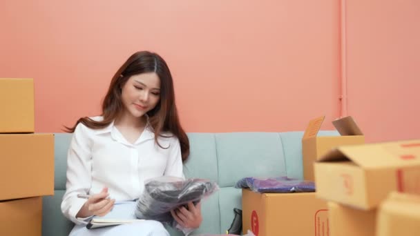 4K解像度のビジネスコンセプト アジアの女性は自宅で顧客の注文をチェックします 記録を 商品のリストを書いて — ストック動画