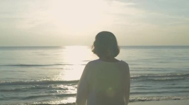 Tatil konsepti 4k Çözünürlük. Yaşlı kadın sahilde yoga yapıyor..