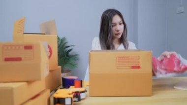 4k Kararlılığın iş konsepti. Asyalı kadın evdeki kutularda ürünleri paketliyor..