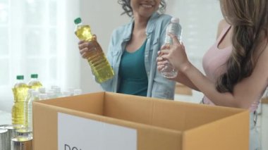 4k Çözünürlük Gönüllü konsepti. Asyalı kadınlar evde bağış kutusunda yiyecek paketliyorlar. Kurbanlara yardım etmek için bağışlanan tüketici malları.