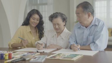 Sanatçı konsepti 4k Çözünürlük. Asyalı aileler oturma odasında bir araya geliyorlar. Sanatçı iş yaratıyor. Boş zaman aktiviteleri ve hobileri.